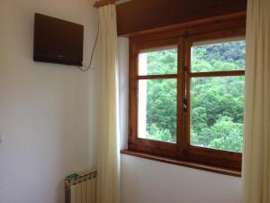 a room with a window and a television on a wall at Hostal Monte Rio in Peñamellera Alta