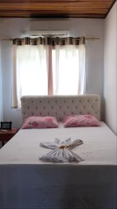 a bed with a dress on it with a window at Flats Paraty in Paraty