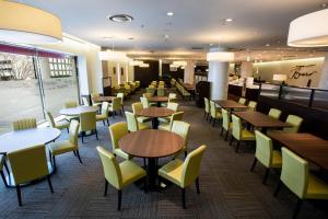 a dining room with tables and yellow chairs at Okura Act City Hotel Hamamatsu in Hamamatsu