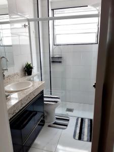 a white bathroom with a sink and a toilet at Apartamento Edifício Turim Ponta da Praia Santos in Santos