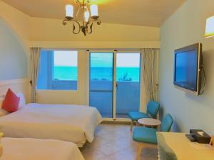 a hotel room with two beds and a flat screen tv at Hotel Bayview in Dahan