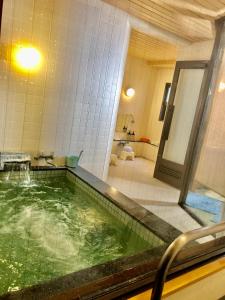 baño con bañera grande con agua verde en Umeoka Ryokan, en Nagano