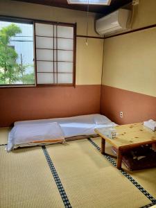 Habitación con cama y mesa. en Umeoka Ryokan, en Nagano