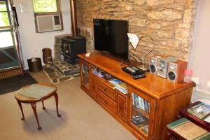 a living room with a television on a wooden entertainment center at Bakehouse Burra in Burra