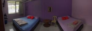duas camas num quarto com paredes roxas em Apple Boutique Homestay em Kuantan
