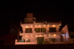een groot wit gebouw met 's nachts een groene deur bij Ganga Monastery in Varanasi