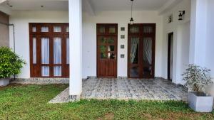 a house with two doors and a grass yard at Elite Holiday Home, Anuradhapura in Anuradhapura