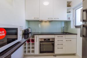 a kitchen with white cabinets and a stove top oven at Casa Beatriz in Carvoeiro