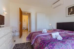a bedroom with a bed with a purple blanket and a tv at Casa Beatriz in Carvoeiro
