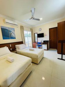 a hotel room with two beds and a television at Hulhan'gu Lodge in Himmafushi