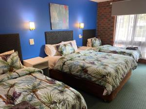 two beds in a hotel room with blue walls at Zero Inn Motel in Nhill +29 photos