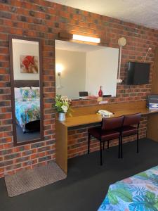 a room with a brick wall with a mirror and a desk at Zero Inn Motel in Nhill