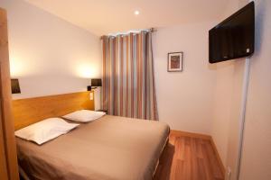 a bedroom with a bed and a flat screen tv at Village Club La Pulka Galibier - Neaclub in Valloire