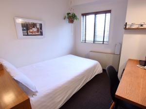 a bedroom with a bed and a desk and a window at Hotel Pacific Kanazawa in Kanazawa