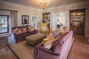 una sala de estar con sofás, sillas y una lámpara de araña. en Lombard Villa en Plettenberg Bay