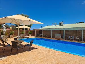 a patio area with chairs, tables and umbrellas at Albion Hotel in Kalgoorlie