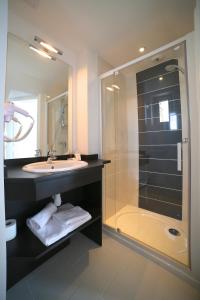 a bathroom with a sink and a shower with a glass door at Hotel Restaurant Le Lion d'Or in Saint-Hilaire-du-Harcouët