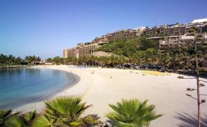 a view of a beach with palm trees and buildings at La Sabina in Mogán