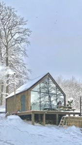 um pequeno edifício com uma grande janela na neve em Szklana Stodoła em Przywidz