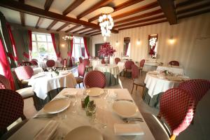 a dining room with white tables and red chairs at Hotel Restaurant Le Lion d'Or in Saint-Hilaire-du-Harcouët