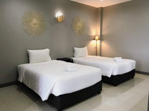 2 camas en una habitación de hotel con sábanas blancas en Grandsiri Resort KhaoYai, en Mu Si