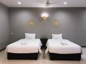 a bedroom with two beds with white sheets and two mirrors at Grandsiri Resort KhaoYai in Mu Si