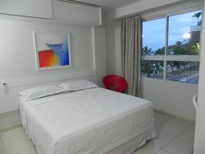 a white bedroom with a bed and a window at Flat Easy Sunset in João Pessoa