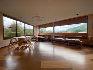 una stanza con tavoli e sedie e ampie finestre di Auberge Mermaid a Fujikawaguchiko