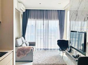 a living room with a couch and a large window at Veranda Residence Pattaya By Fon in Na Jomtien +4 photos