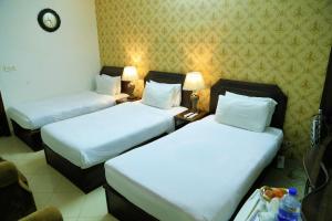 two beds in a hotel room with white sheets at Fiesta Inn Hotel & Resorts Multan in Multan