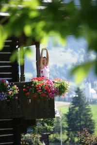 a woman is sitting on a balcony with flowers at Leebhof in Patergassen