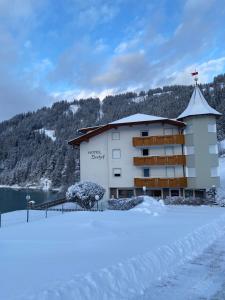 ein Gebäude mit Schnee auf dem Boden davor in der Unterkunft Hotel Seehof in Welsberg-Taisten