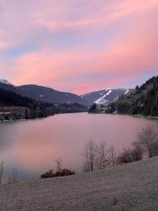 a view of a lake at sunset with mountains at Hotel Seehof in Monguelfo
