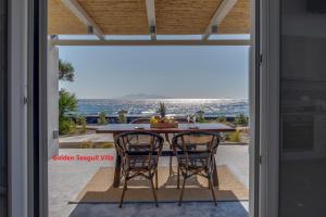 een eettafel met 2 stoelen voor een glazen deur bij Blue Magic Villas in Agia Paraskevi