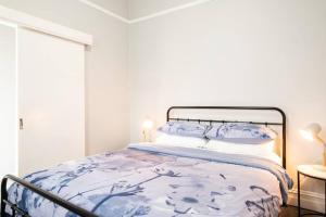 a bedroom with a bed with a blue and white comforter at Quartz Cottage Geelong in Geelong