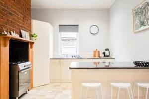 a kitchen with white walls and a counter with stools at Quartz Cottage Geelong in Geelong