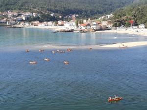 een groep mensen in kajaks in het water bij een strand bij Río Ézaro in O Pindo