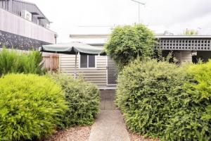 a garden with bushes and an umbrella next to a building at Quartz Cottage Geelong in Geelong