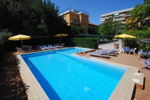 a large swimming pool with chairs and umbrellas at Hotel Caravelle in Pesaro