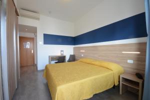 a bedroom with a yellow bed and a blue wall at Hotel Caravelle in Pesaro