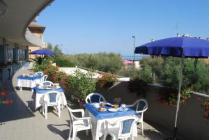 a group of tables and chairs with an umbrella at Hotel Caravelle in Pesaro