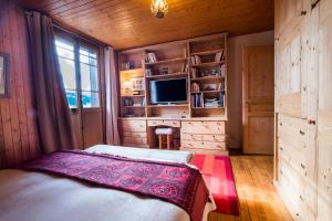 een slaapkamer met een bed, een bureau en een televisie bij CHALET Les Chouchous in Passy