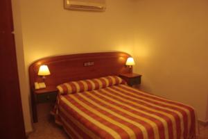 una habitación de hotel con una cama con dos lámparas. en Gran Hostal Asador de Soto, en Soto Real
