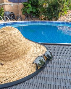 un sombrero de paja y gafas de sol sentadas junto a una piscina en Lua Pousada, en Barra de São Miguel