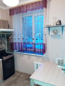 ノヴォシビルスクにあるApartments home hotelのキッチン(青いカーテンとカウンター付きの窓付)