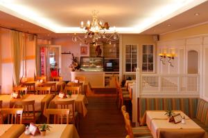 a restaurant with tables and chairs and a chandelier at Seehotel ZUR MÜNZ in Meersburg