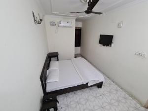 a small white room with a bed and a tv at Hotel Victoria in Chandīgarh