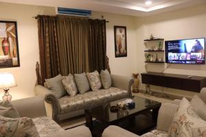 a living room with a couch and a flat screen tv at Elegant & Charming One Bed Apartment In Bahria Town in Rawalpindi