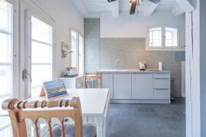 フーズムにあるAltes Kontorhaus Backbordの白いキャビネット、テーブルと椅子付きのキッチンが備わります。