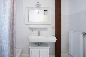 a white bathroom with a sink and a mirror at Altes Kontorhaus Steuerbord in Husum